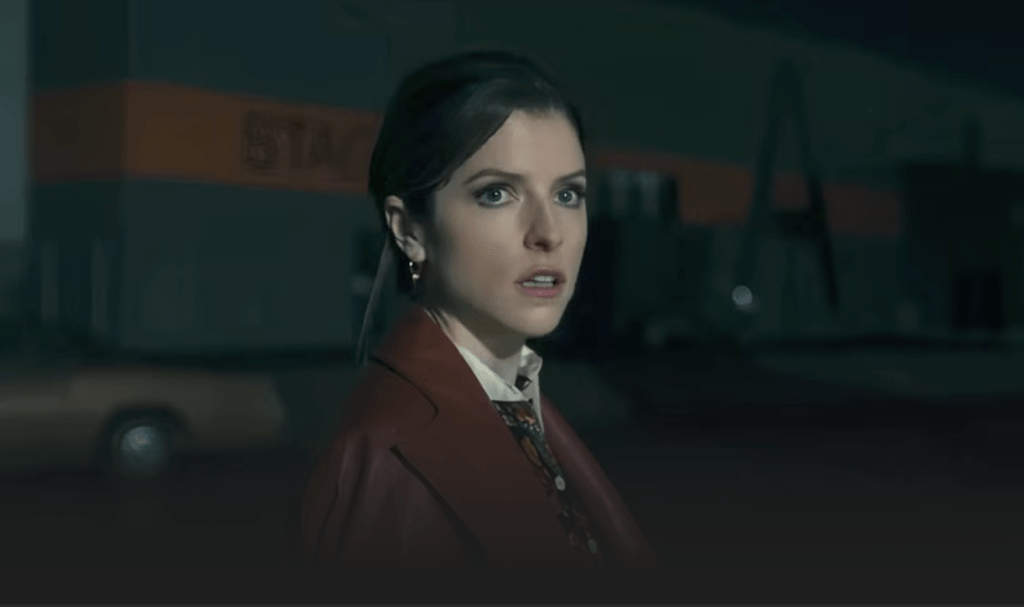 Anna Kendrick standing alert at night in Woman of the Hour, showing a woman’s quiet vigilance.