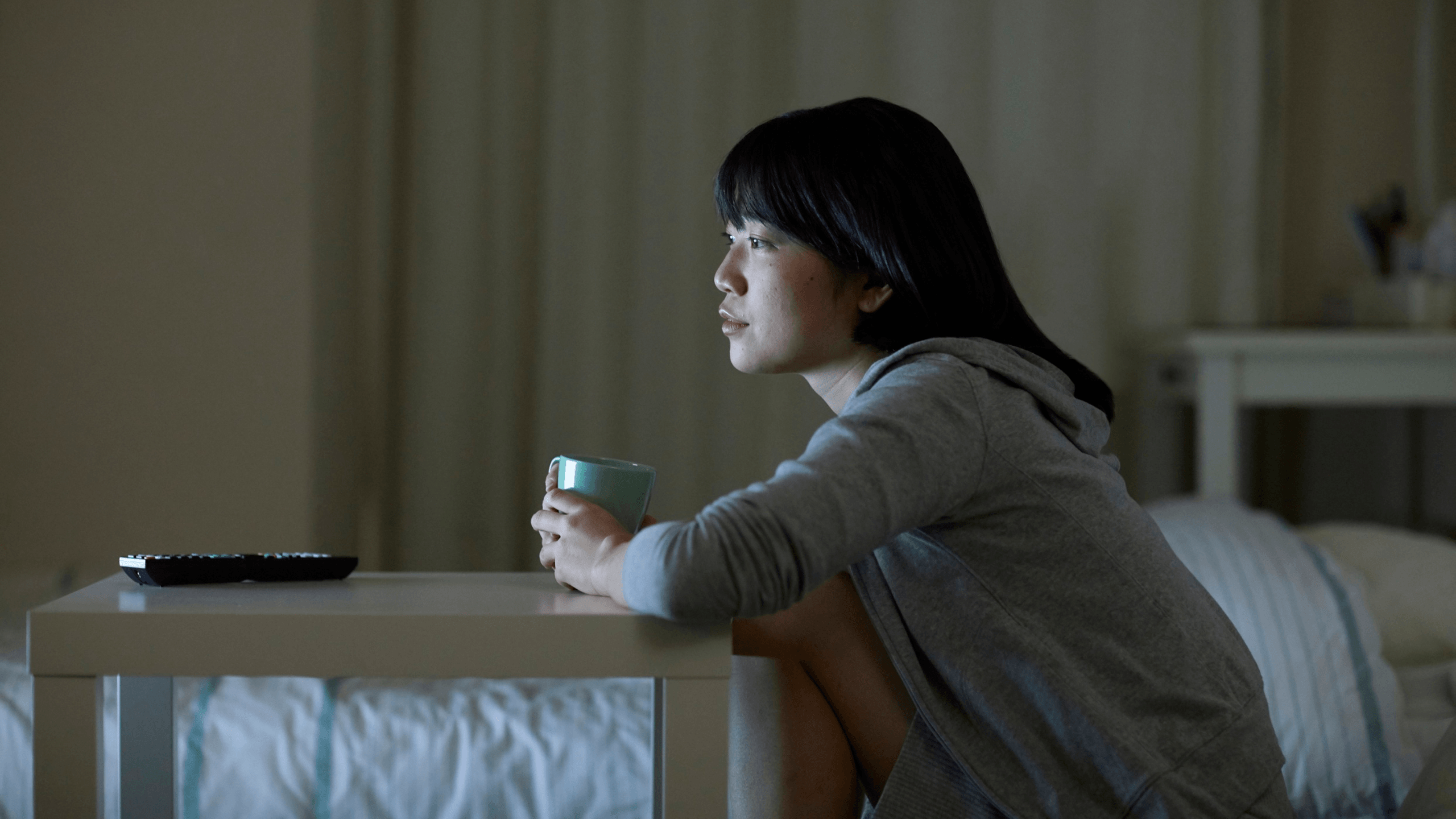 A woman illuminated by soft screen light, absorbing survival knowledge from true crime media.