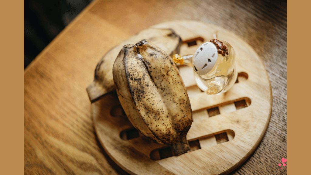 The Male Loneliness Epidemic - Rotten bananas resting beside a glass figurine on a wooden plate, under soft light.