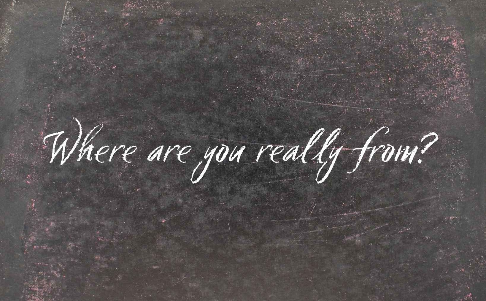 Microaggressions - The phrase “Where are you really from?” written in white script on a worn blackboard background.