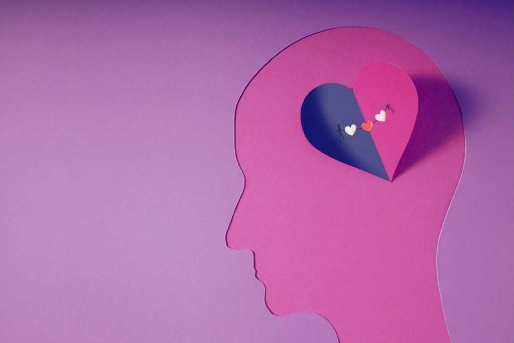 Why we ignore red flags in love - illustration of a human head silhouette with a heart‑shaped cutout containing small hearts, symbolizing how the brain rewires itself in early love.