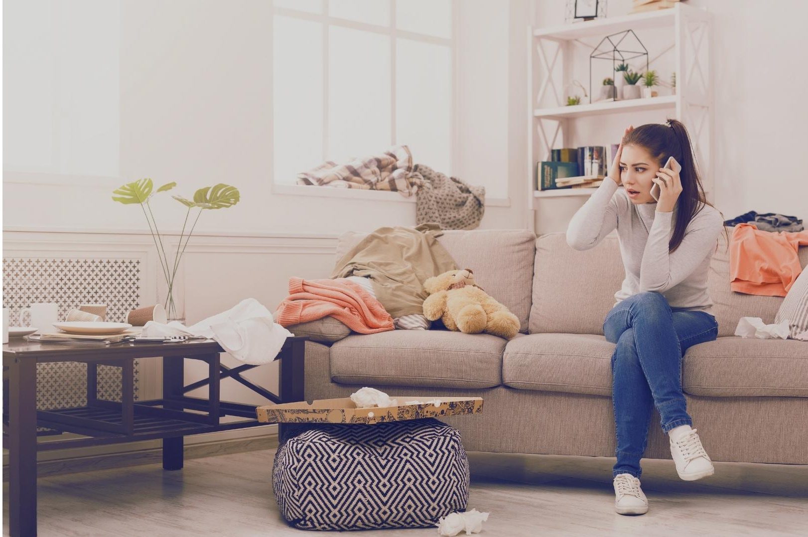 Simple life and social comparison – stressed woman on the phone in a messy living room with clothes and boxes everywhere.