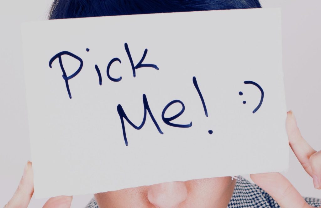 Pick Me Girl - A girl holding sign that says “Pick Me” representing the pick me girl label and social belonging dynamics